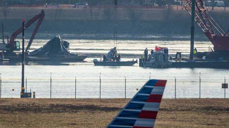 Salvage crews lift a piece of wreckage from the water at the site in the Potomac River of a...