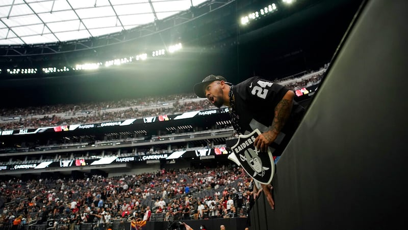 A Las Vegas Raiders fans cheers before an NFL football game against the Arizona Cardinals...