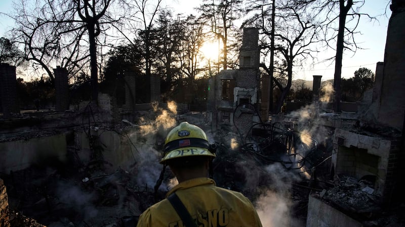 Firefighters put out a hot spot at a home destroyed by the Eaton Fire, Tuesday, Jan. 14, 2025,...