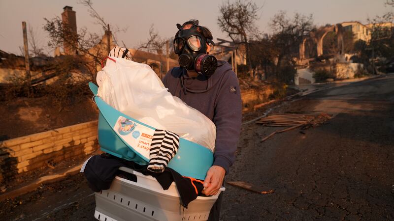 Josh Lederer wears a mask to protect him from fumes as he retrieves his children's clothes...