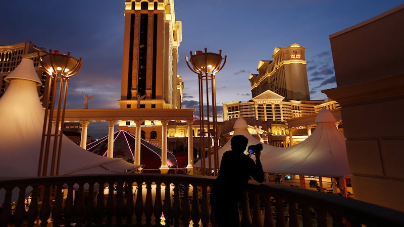 FILE - A man takes pictures of Caesars Palace hotel and casino in Las Vegas, Jan. 12, 2015....