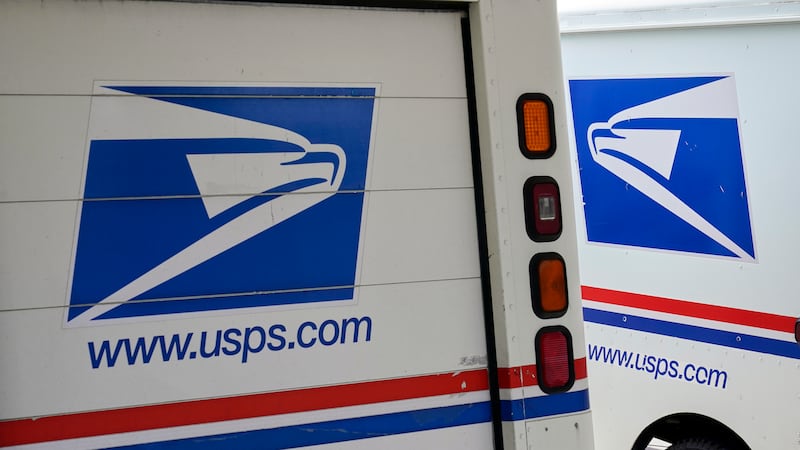 FILE - In this Aug. 18, 2020, file photo, mail delivery vehicles are parked outside a post...