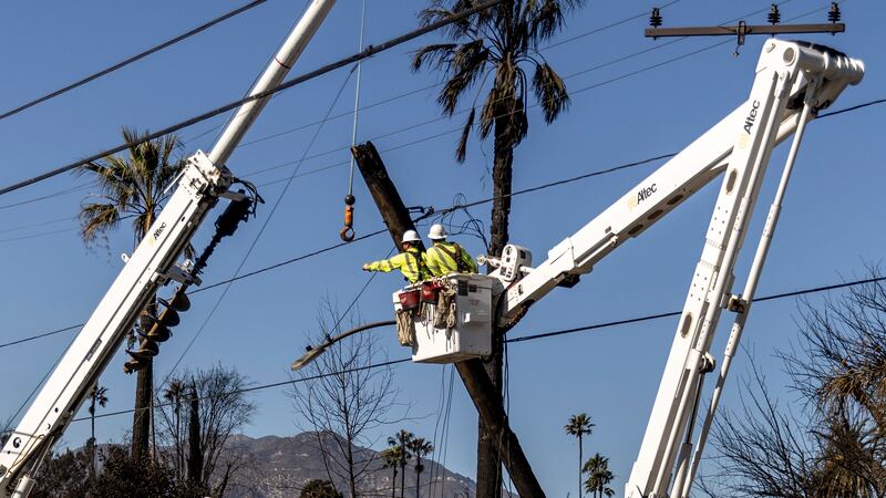 Workers with Southern California Edison remove a utility pole damaged by the Eaton Fire in...