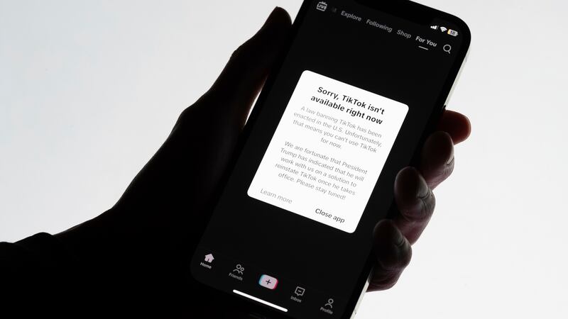 A message reading "Sorry, TikTok isn't available right now" is displayed on a cell phone...
