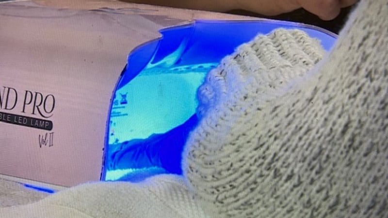 gel manicure client uses UV light to cure the polish