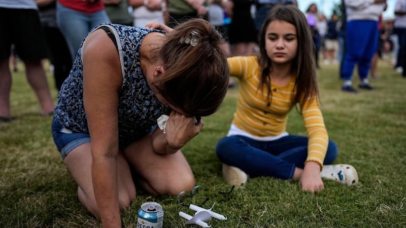 Brandy Rickaba and her daughter Emilie pray during a candlelight vigil for the slain students...
