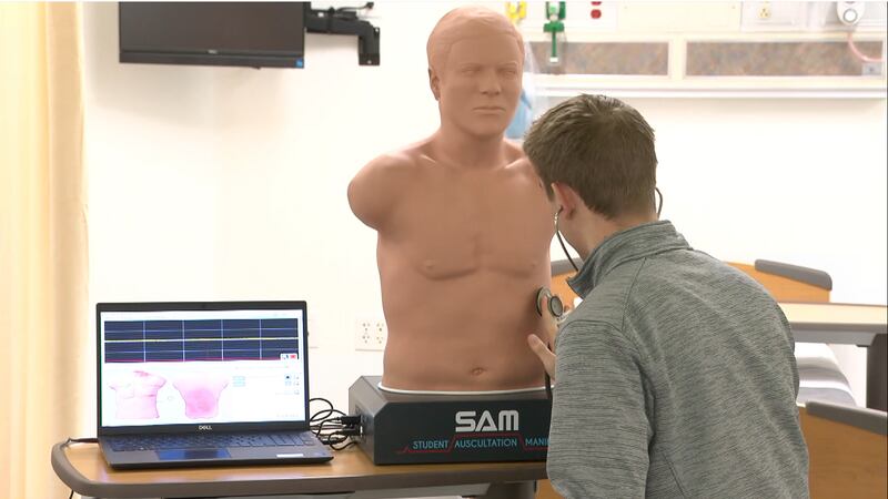 A Touro University students takes the vital signs of a high-fidelity mannequin in the school's...