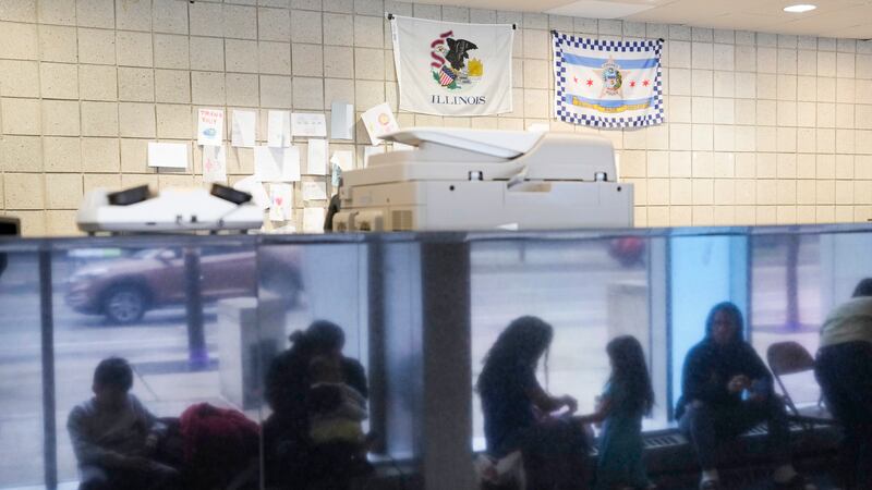 FILE - Immigrants from Venezuela are reflected in a marble wall while taking shelter at the...